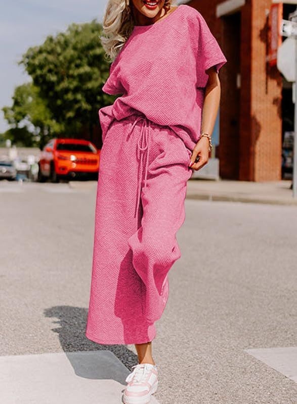 Women's pink solid color two-piece set with short-sleeved top and trousers, made of polyester.