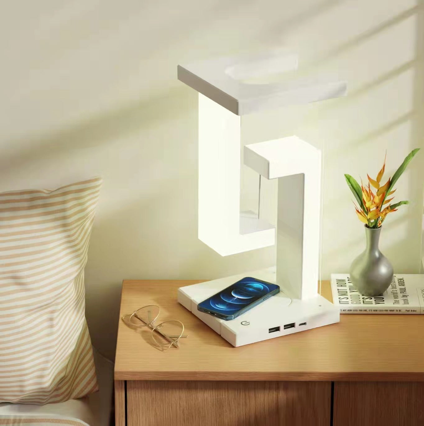 Wireless charging suspension table lamp with smartphone, on a bedside table.