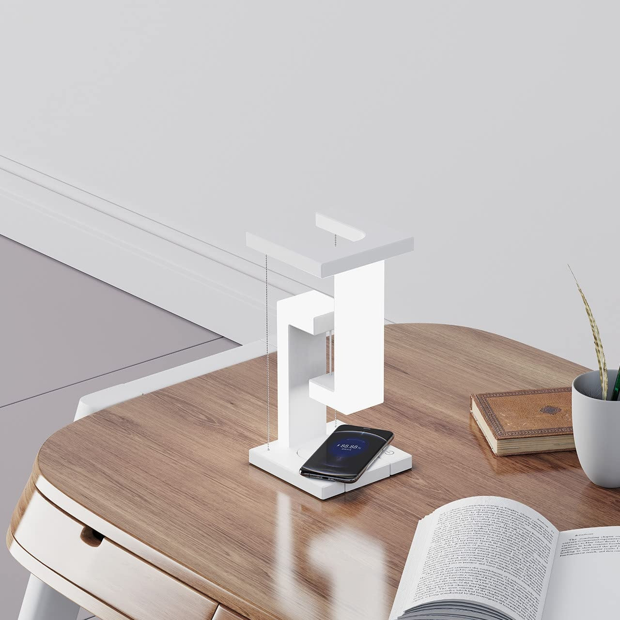 Modern white table lamp with wireless charging and floating design on a wooden desk.